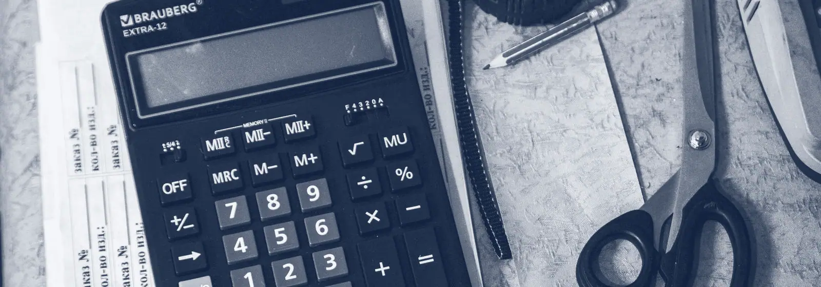 Calculatrice posée sur des papiers, avec un crayon et des ciseaux
